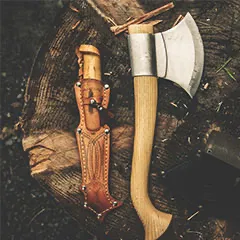Knife in Scabbard and Axe on a Rustic Background